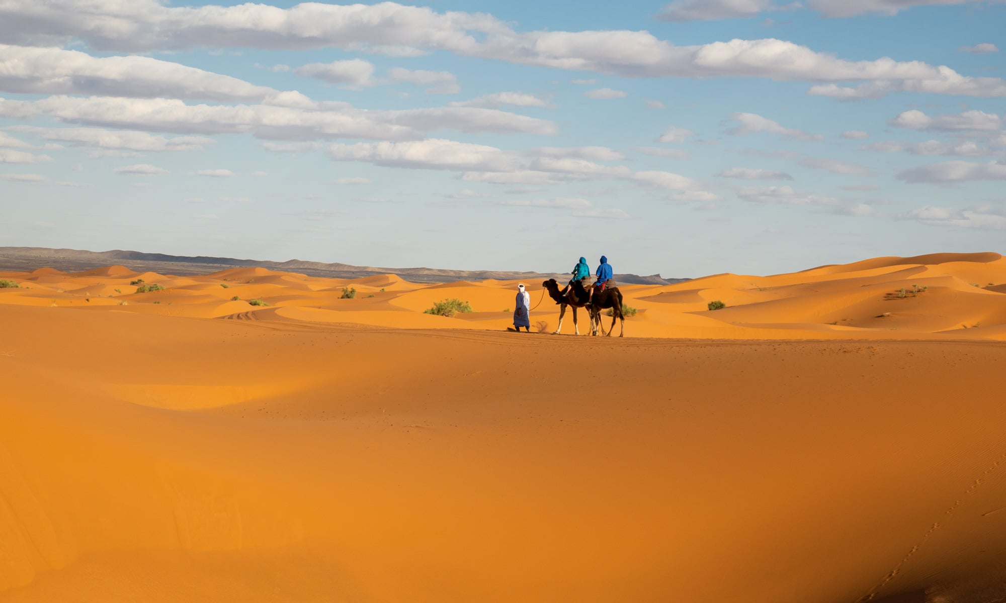 view of two riders on a camel in Moroccan desert